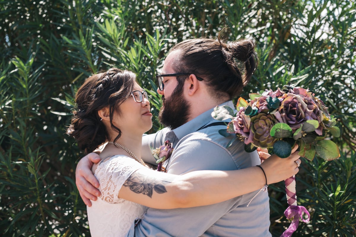 Romantic moment as the husband holds his new bride in his arms, sharing a loving gaze after their intimate wedding at All Inclusive Weddings Orlando.