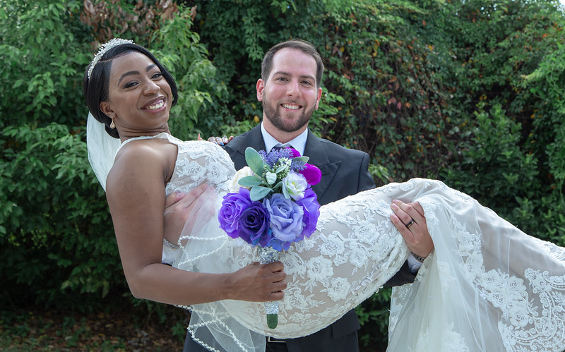 Heartwarming moment as the husband lovingly carries his new wife in his arms, captured at All Inclusive Weddings Orlando.