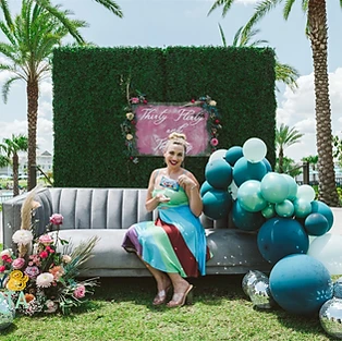 Step into a whimsical wonderland with our stunning wedding couch setup by Simply Enchanted Events. Guests can relax and strike a pose on the plush couches nestled against a backdrop of lush green grass wall adorned with vibrant balloons and delicate flowers. This picture-perfect seating oasis creates a captivating ambiance, perfect for capturing beautiful moments and creating lasting memories. Immerse yourself in the enchantment of All Inclusive Weddings Orlando, where every detail is meticulously designed to make your special day truly unforgettable