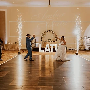 Experience the magic of the dance floor as the husband and bride twirl and sway in each other's arms, surrounded by an electrifying atmosphere created by Simply Enchanted Events. The air is filled with excitement as crazy large sparklers illuminate the space, casting a mesmerizing glow. Their names are projected on the wall, adding a personal touch to the celebration. This enchanting moment captures the joy and love shared between the newlyweds, making for an unforgettable and captivating experience at All Inclusive Weddings Orlando.