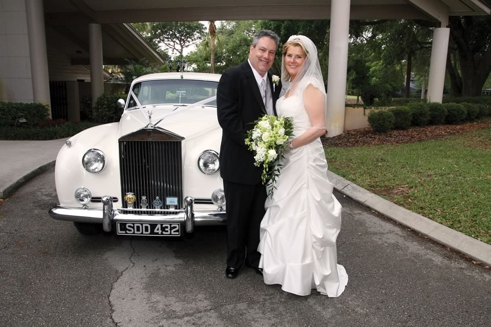 Smiling Couple in Front of a 1965 Rolls-Royce Silver Cloud by VIP Wedding Transportation