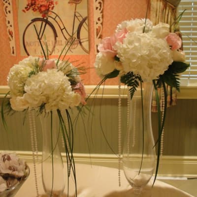 A table display featuring exquisite vases filled with a combination of white and pink flowers, adding a touch of beauty to the setting.