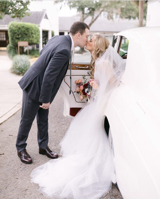 Romantic Moment: Husband kissing wife as she gets in the classic ride from VIP Wedding Transportation