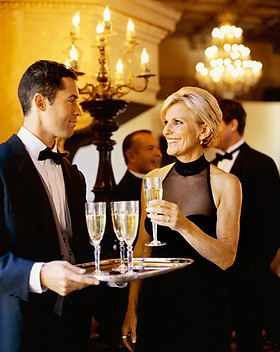 Server Serving Drinks to Smiling Guests by Cocktails Catering