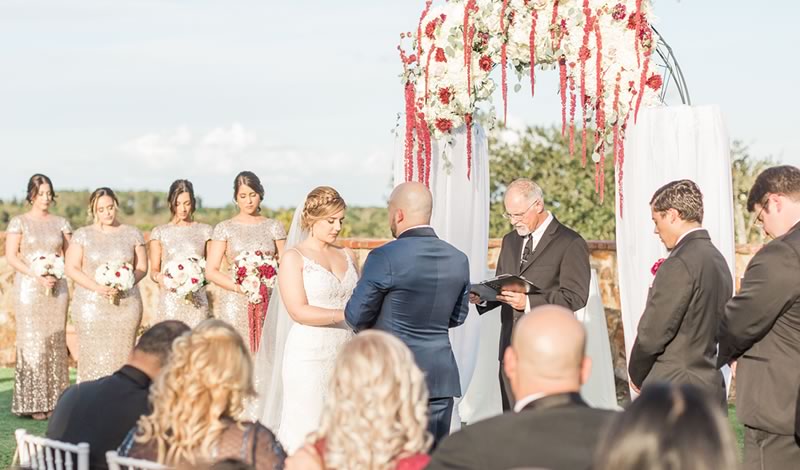 Captivating wedding ceremony officiated by Ceremonies By Ray at Garden Villa. The bride, groom, bridesmaids, and groomsmen stand with heads bowed in anticipation of Ray's heartfelt words at All Inclusive Weddings Orlando