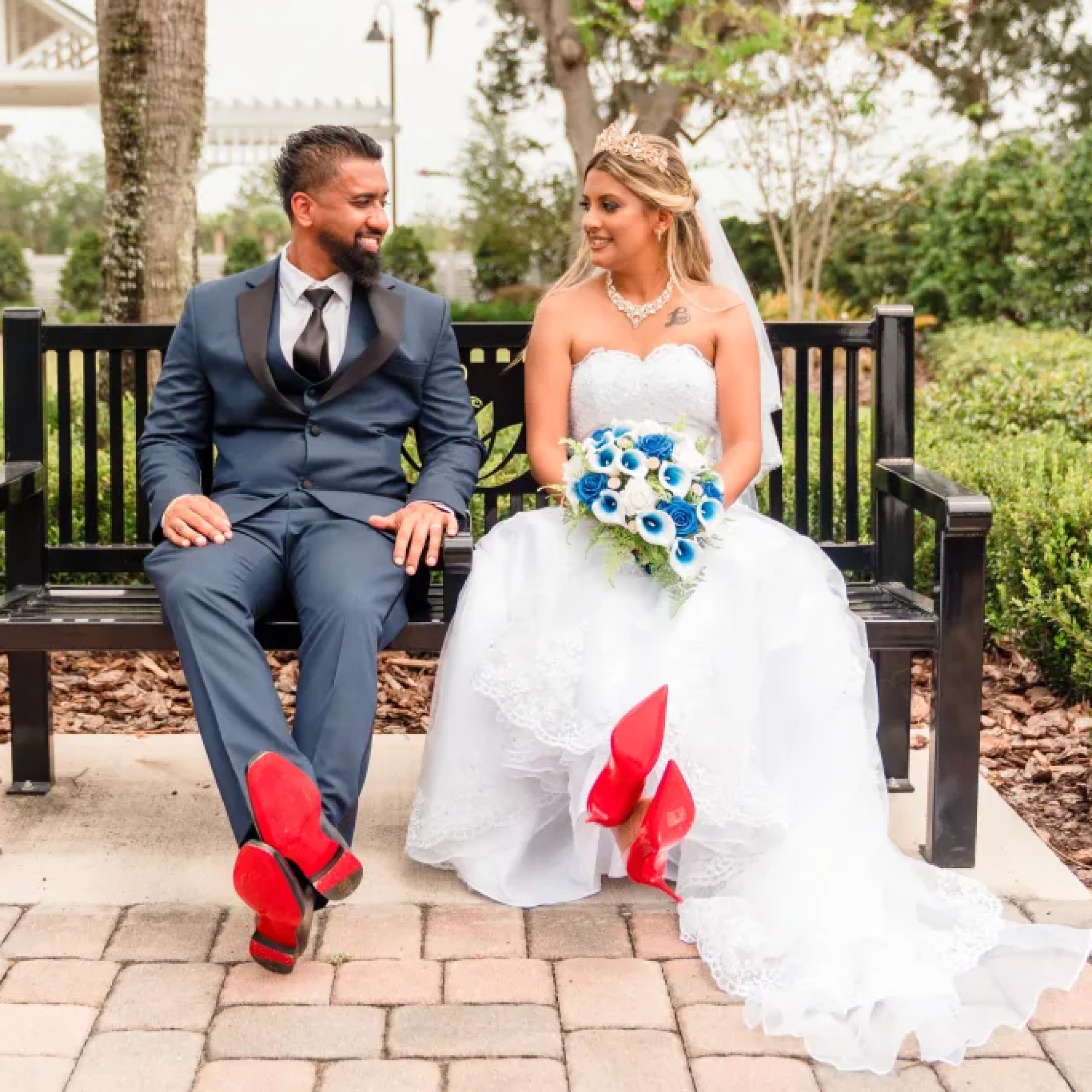 The bride and groom sitting on a bench, radiating joy and style with their sharp outfits and red bottom shoes at All Inclusive Weddings Orlando - Jerzy Nieves Photography