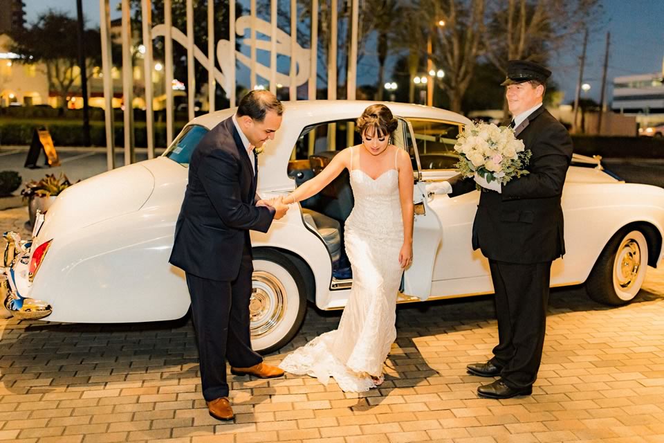 VIP Wedding Transportation: Choffer holding flowers for the bride as the husband assists her out of the 57 Rolls-Royce Silver Cloud Diana