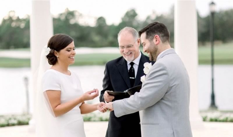 Ceremonies By Ray at All Inclusive Weddings Orlando, capturing the touching moment as the bride delicately places the wedding ring on the groom's hand, symbolizing their commitment and unity