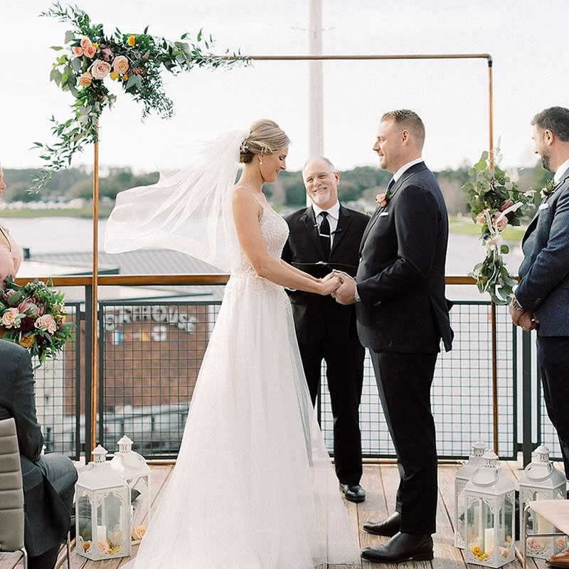 Ceremonies By Ray at All Inclusive Weddings Orlando, capturing the tender moment as the groom shares his heartfelt vows. Ray, the officiant, smiles warmly, witnessing the couple's love and commitment