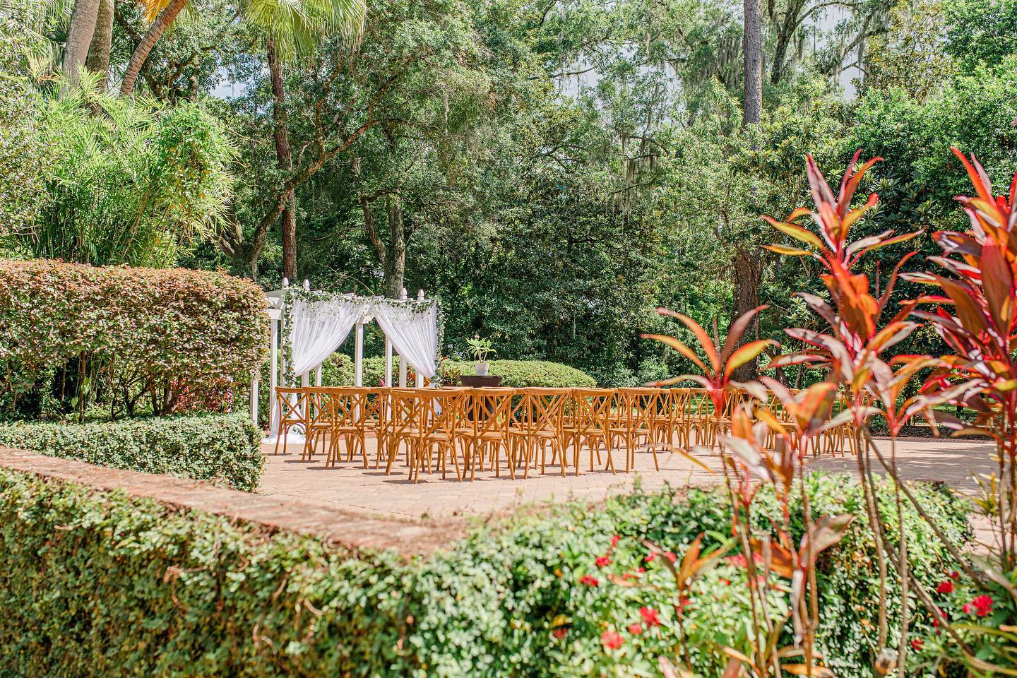 Experience the enchantment of The Garden Villa at All Inclusive Weddings Orlando. A picturesque view of the outdoor garden ceremony setup with beautifully arranged chairs and an elegant altar awaits you