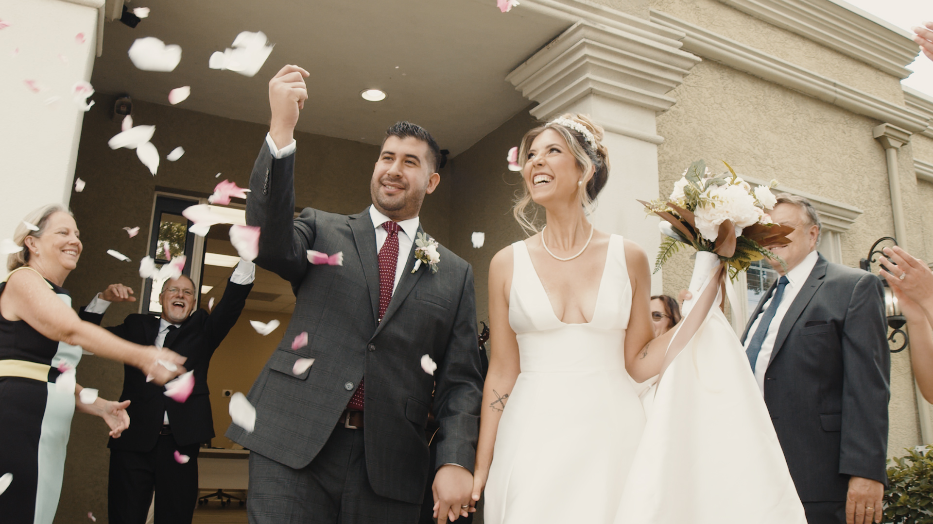 Bride and groom joyfully walking out of the venue with guests showering them with rose petals at All Inclusive Weddings Orlando