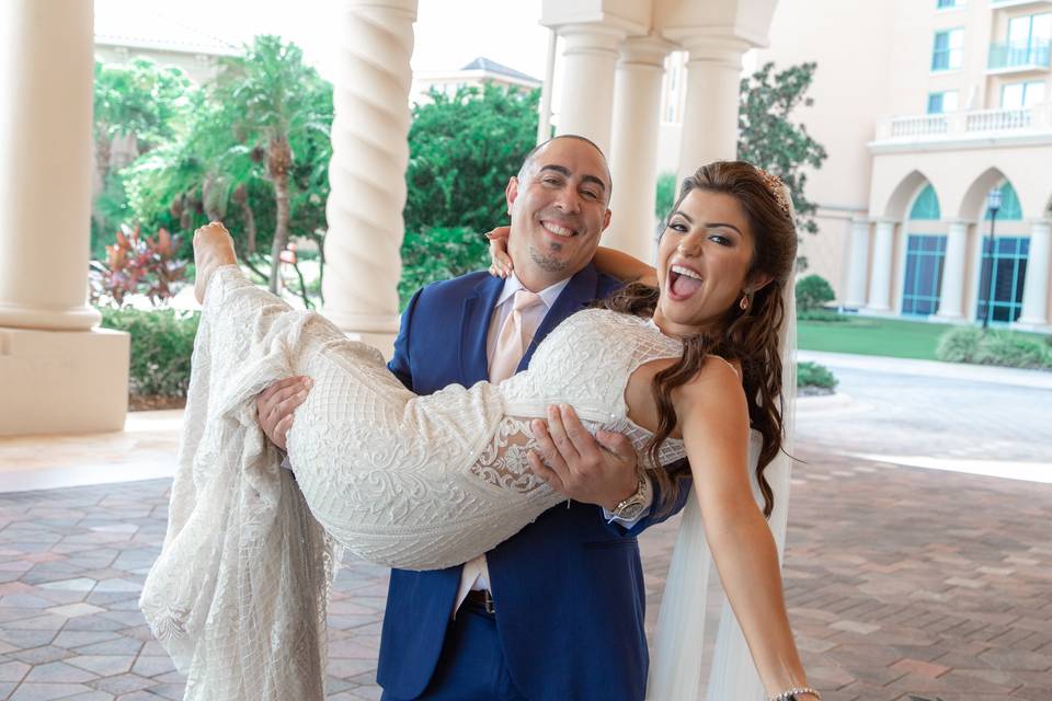 A tender and romantic wedding photo captured by DeMarco Films, showcasing the groom lifting his bride in his arms while they share a joyful smile. The couple's love and happiness radiate through the image, creating a memorable and enchanting moment