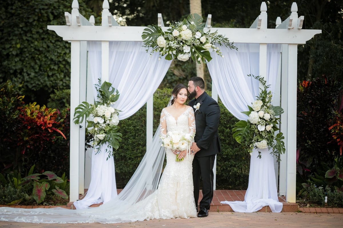 Husband tenderly kissing his wife's head at the altar for a photo at All Inclusive Weddings Orlando