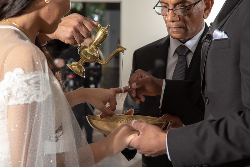 Couple participating in a traditional ritual with a liquid being dropped on a rope tied to the bride's finger at All Inclusive Weddings Orlando