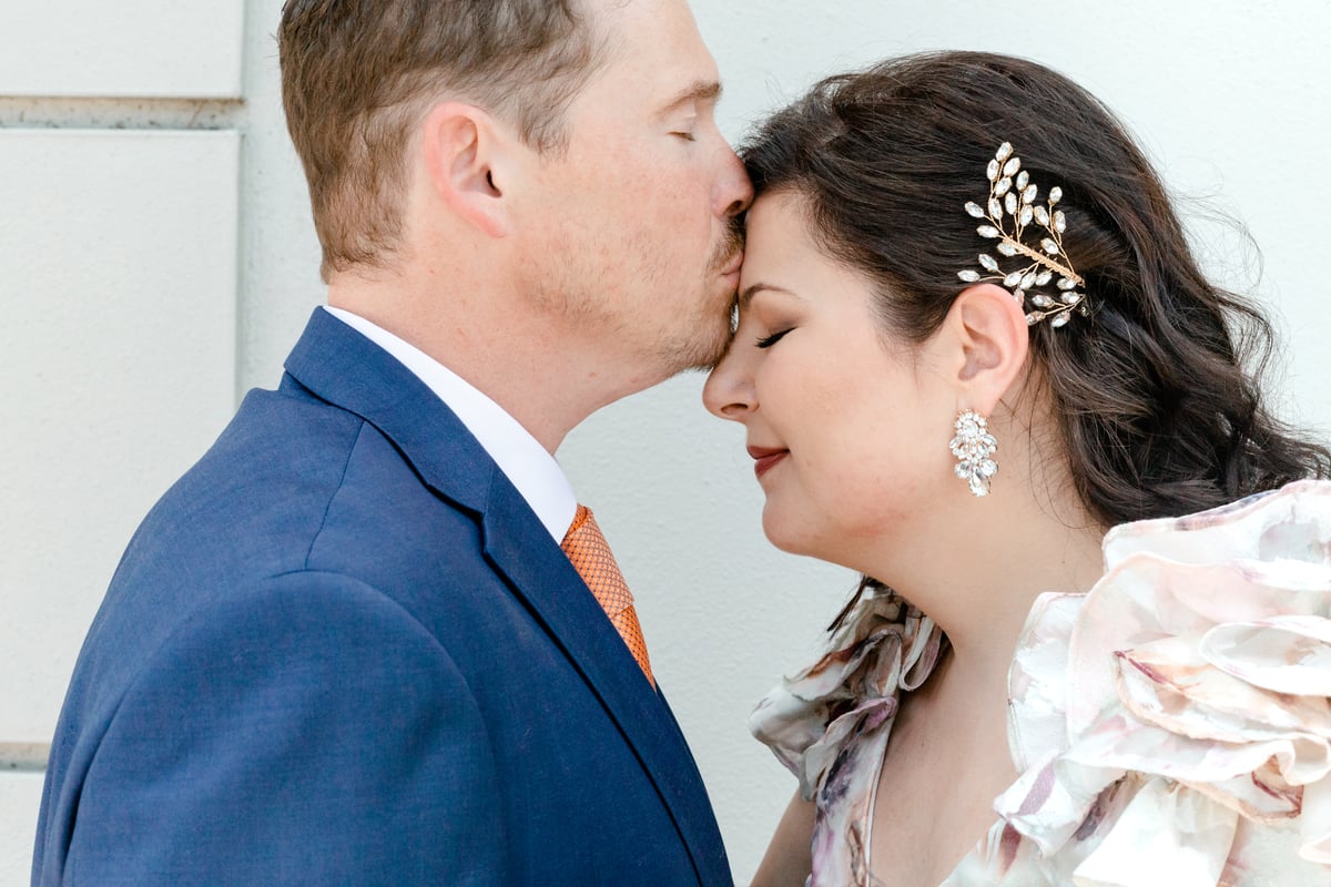 Husband lovingly kissing his wife's forehead, capturing a tender moment of love at All Inclusive Weddings Orlando