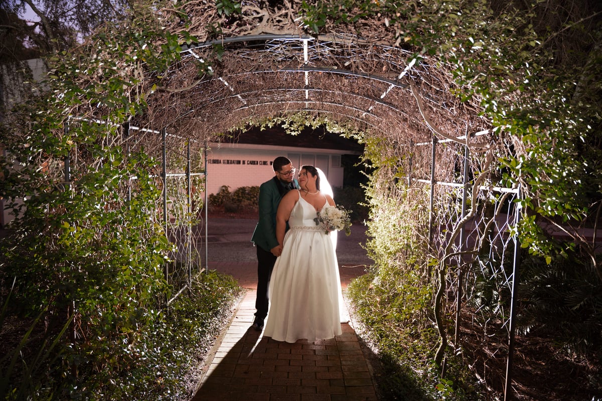 Husband and wife walking through a picturesque tunnel adorned with beautiful foliage at Garden Villa, a stunning wedding venue at All Inclusive Weddings Orlando