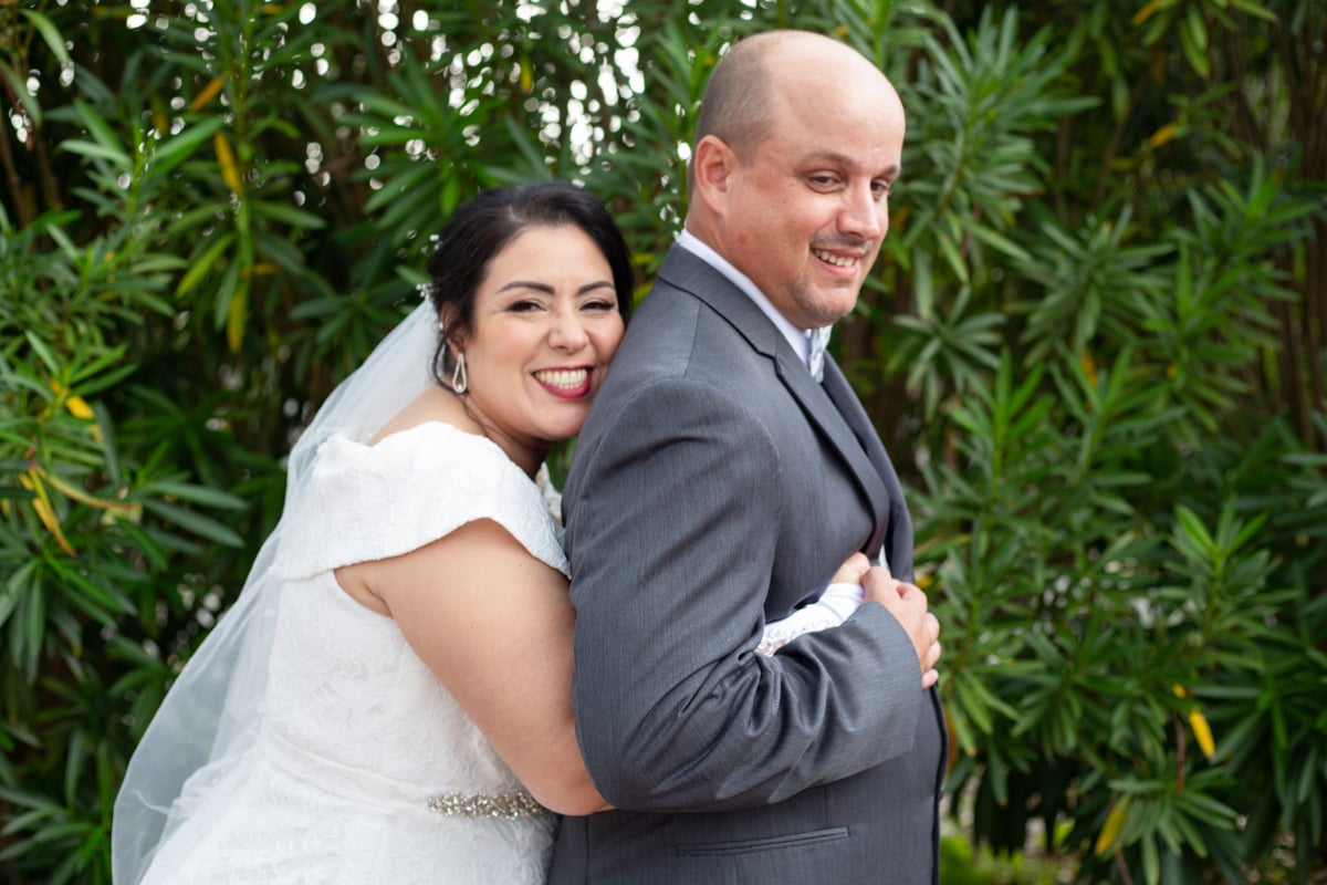 Wife hugging her husband from behind, both smiling, captured in a perfect moment at All Inclusive Weddings Orlando.